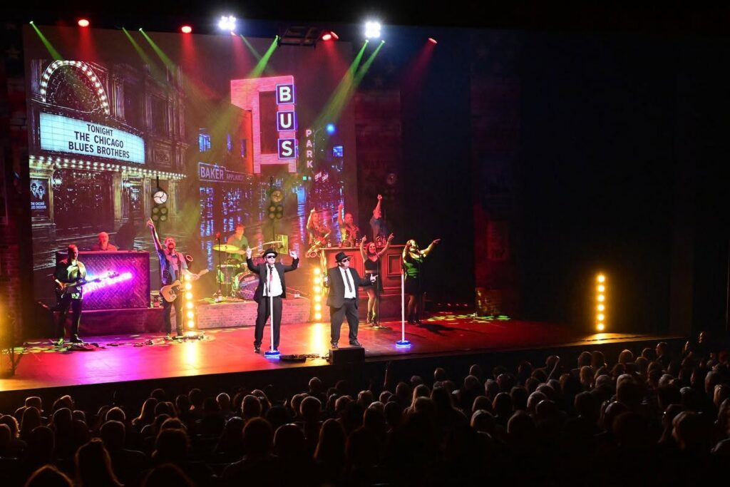 The Chicago Blues Brothers on stage in front of a packed theatre audience